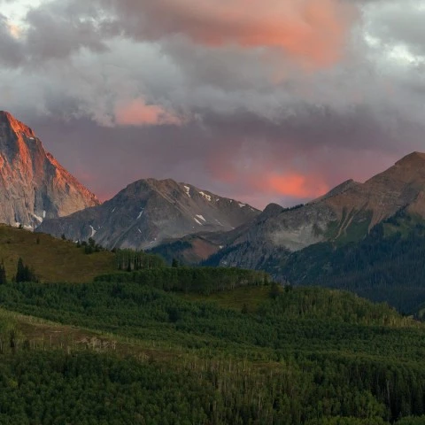 a mountain range with trees and clouds