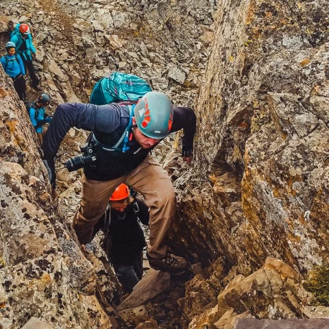 a man in a helmet climbing a rocky cliff