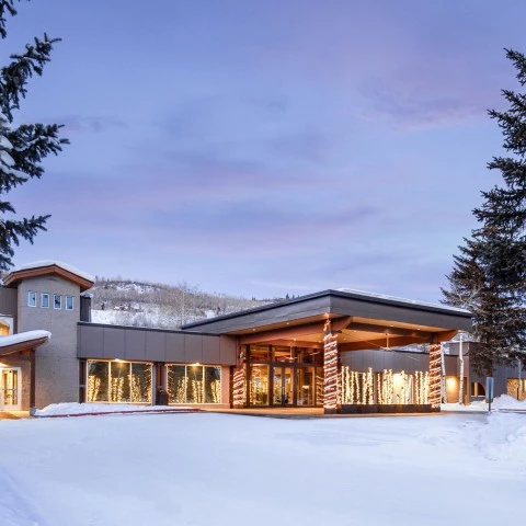 a building with lights and trees in the snow