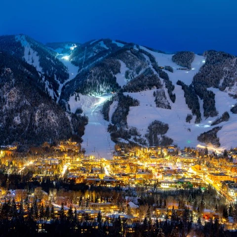 a city lit up at night with mountains in the background