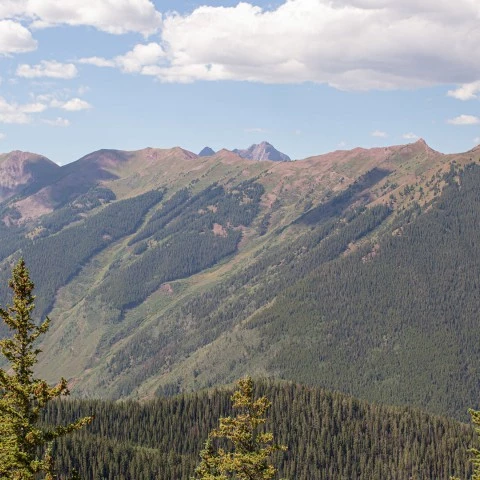 a mountain range with trees and clouds
