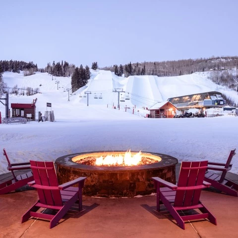 chairs and chairs around a fire pit in the snow