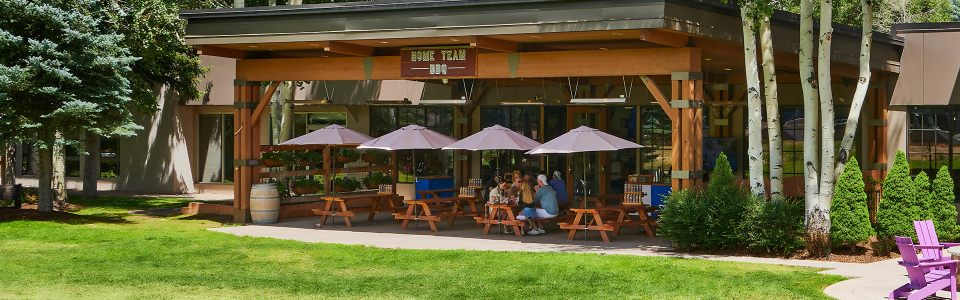 a group of people sitting at tables under umbrellas