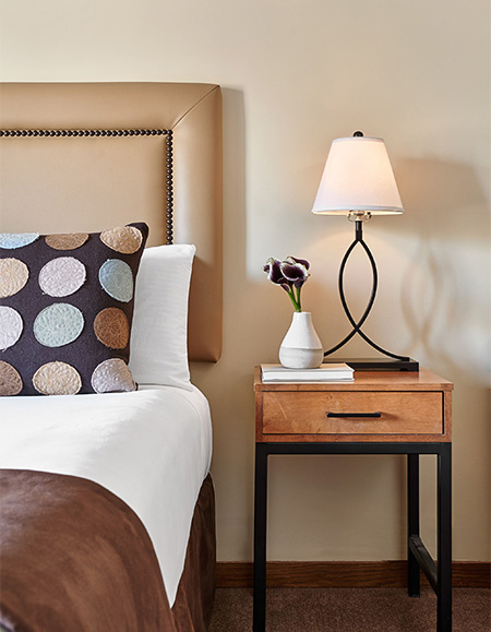 a lamp on a table next to a bed