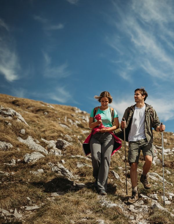a man and woman hiking on a rocky hill