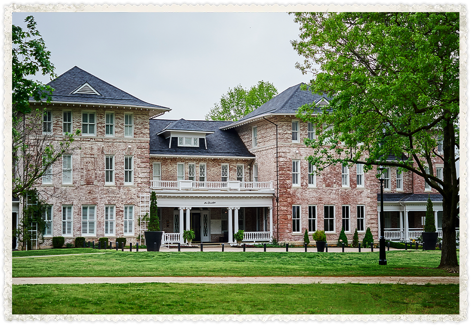 a large brick building with a lawn and trees