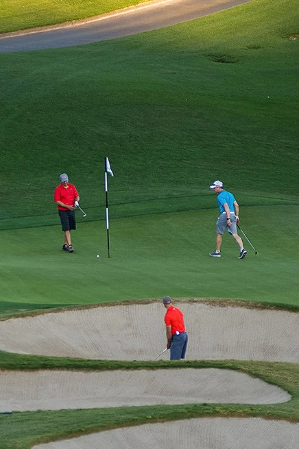 overhead view of 3 men walking around golf course