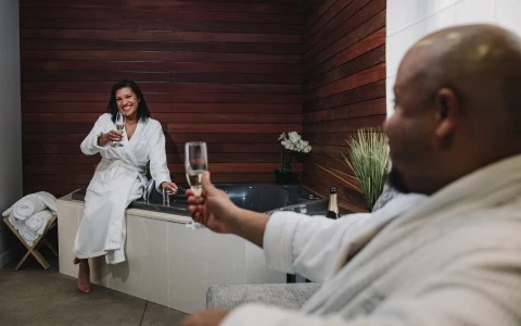 a man and woman in a bathrobe drinking champagne