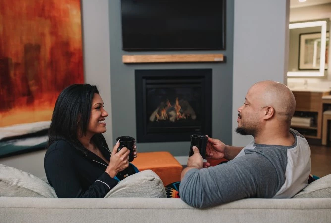 a man and woman sitting on a couch and holding coffee cups