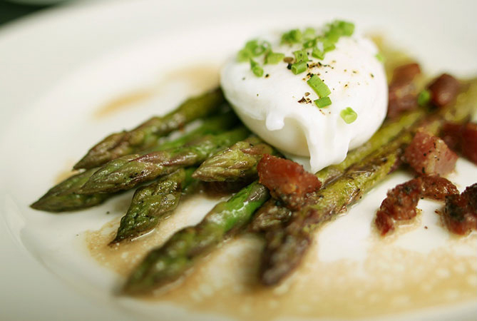 asparagus on white plate with poached egg on top