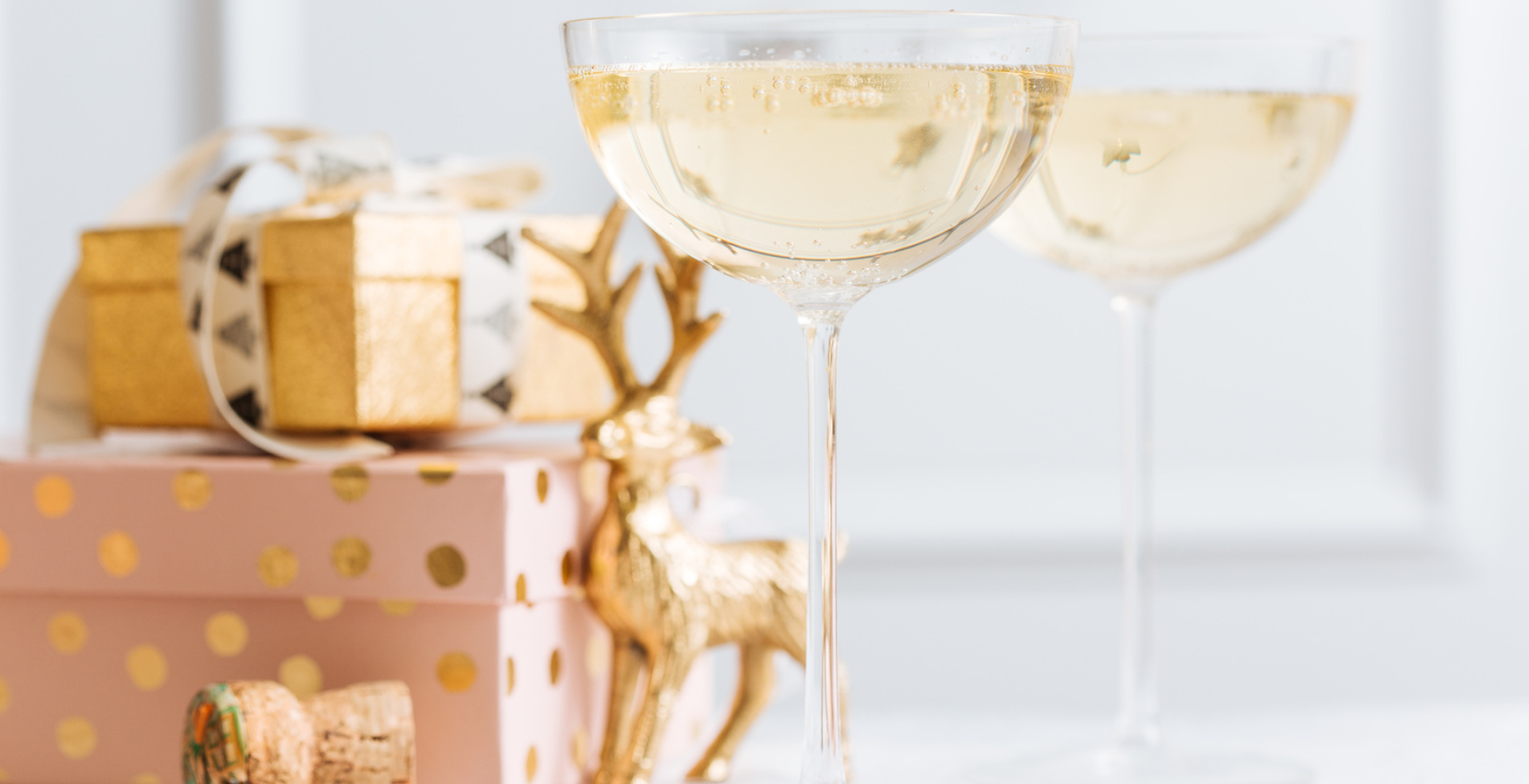 a glass of champagne next to a box of presents