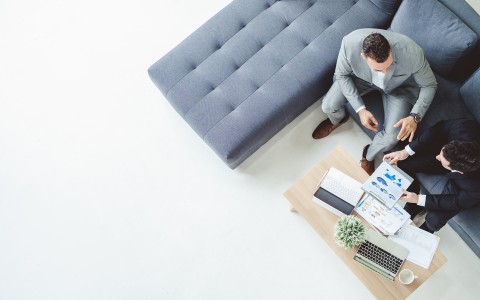 a man sitting on a couch looking at a laptop