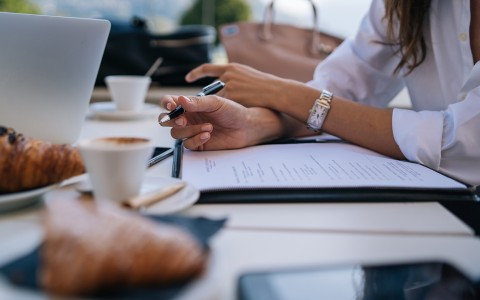 a woman holding a pen and writing on a paper