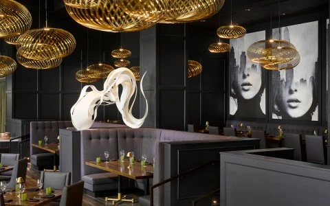 a room with a booth and a table and chandeliers