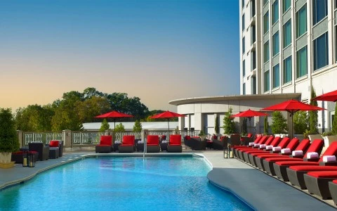 a pool with red chairs and umbrellas
