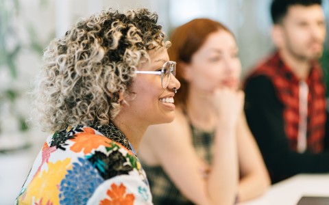 a woman with curly hair and glasses smiling