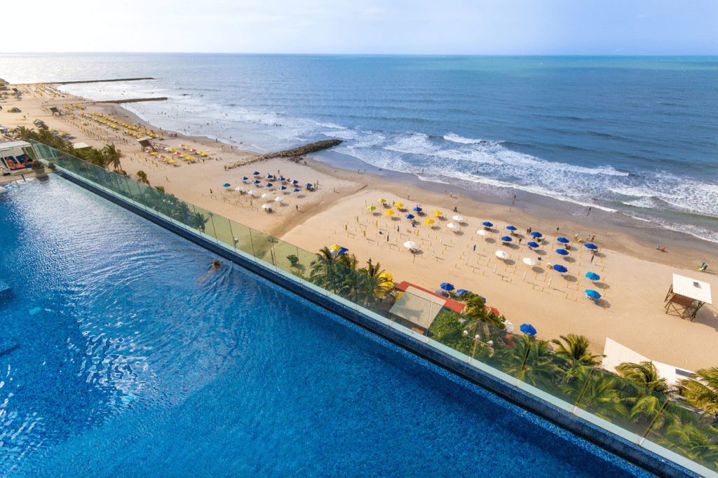 a pool with a beach and umbrellas