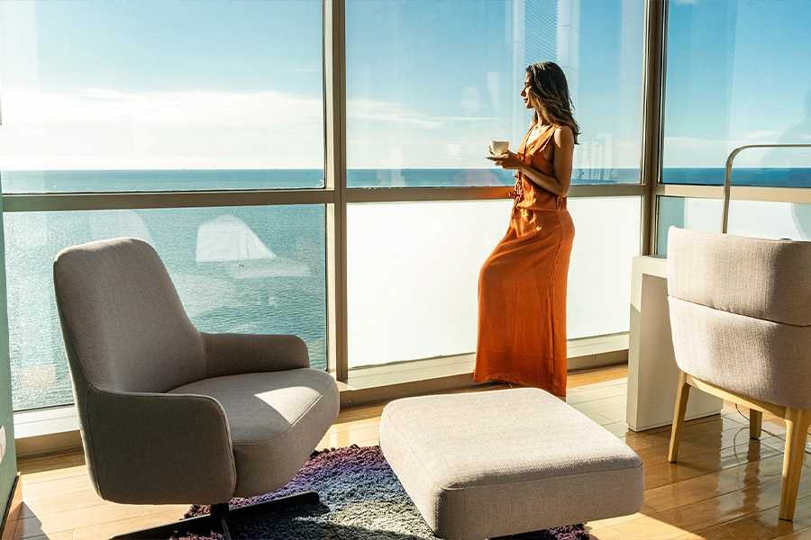 a woman in a dress holding a cup in front of a window