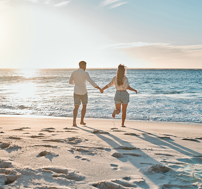 a man and woman holding hands on a beach