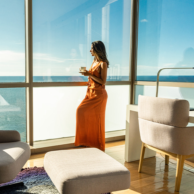 a woman standing in front of a window with a cup of coffee