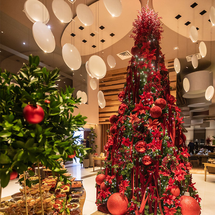 a large christmas tree with red decorations and white balloons