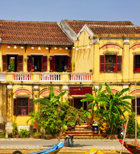 a yellow building with a balcony and trees