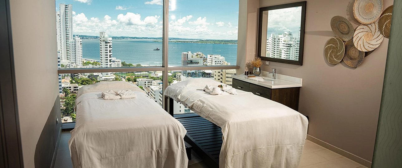 two beds in a room with a view of the ocean