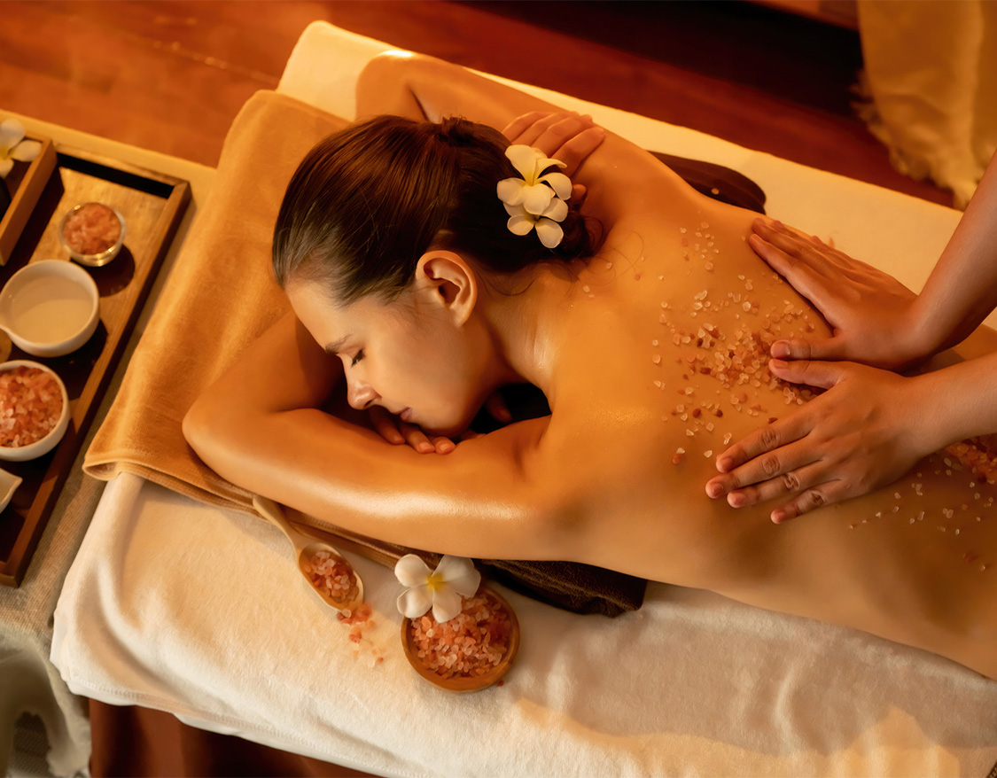 a woman lying down on a massage table with salt on her back