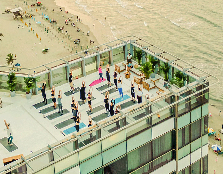 a group of people standing on a rooftop overlooking a beach