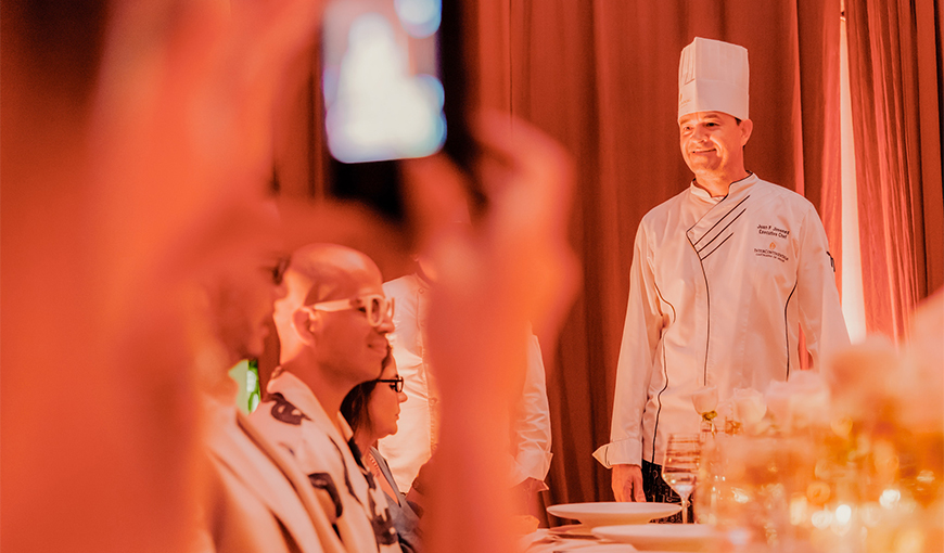 a man in a chef's uniform standing in front of a group of people