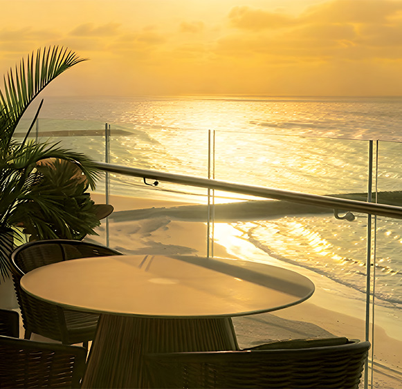 a table and chairs on a balcony overlooking a beach