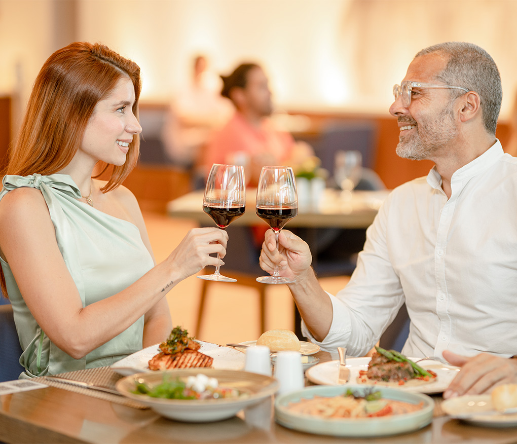 a man and woman holding wine glasses at a restaurant