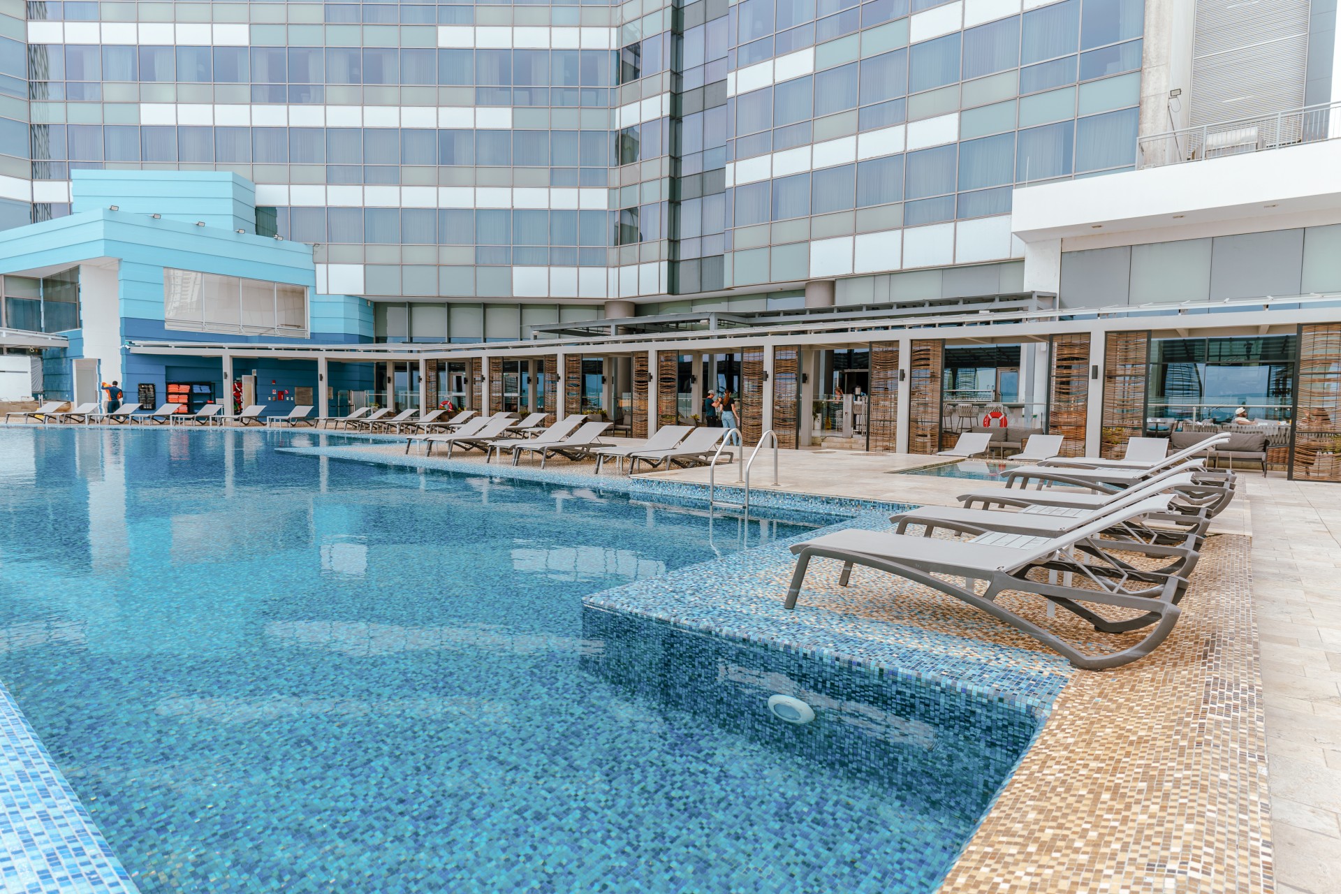 a pool with lounge chairs and a building