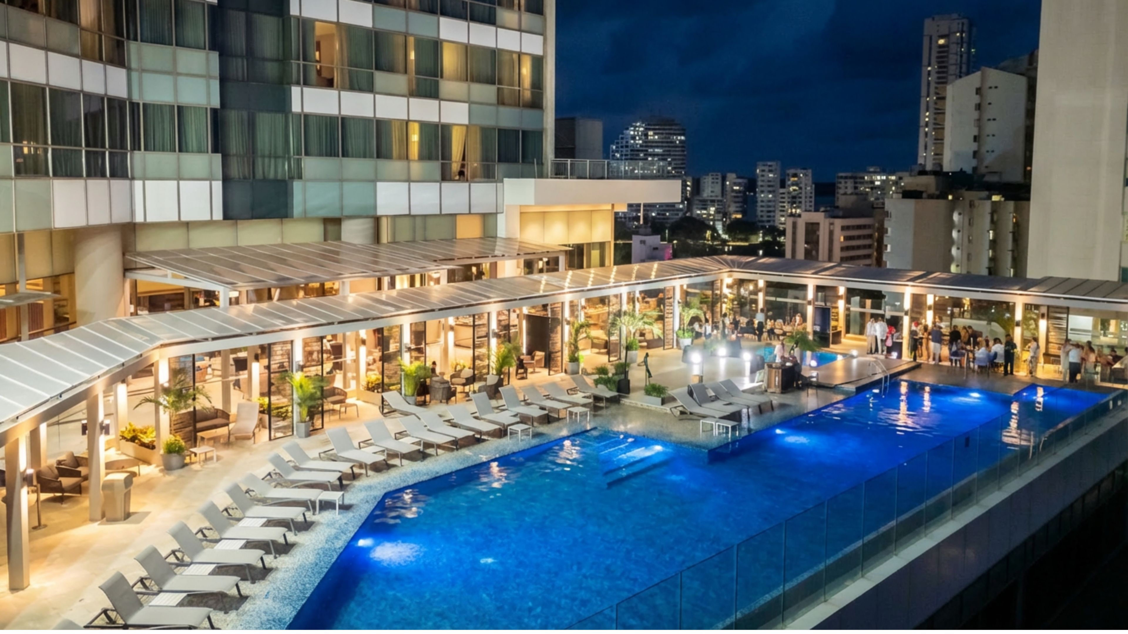 a pool with lounge chairs and a building with a city in the background