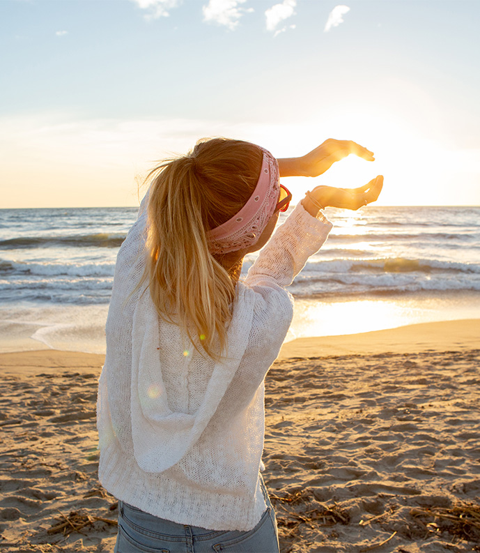 a woman on a beach holding her hands up