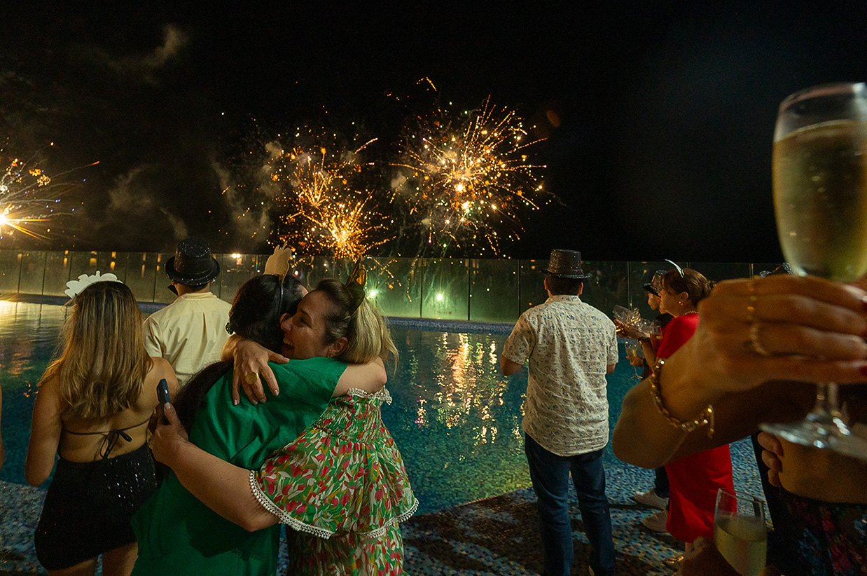 a group of people hugging by a pool with fireworks