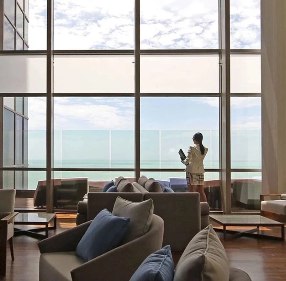 a woman standing in a room with large windows