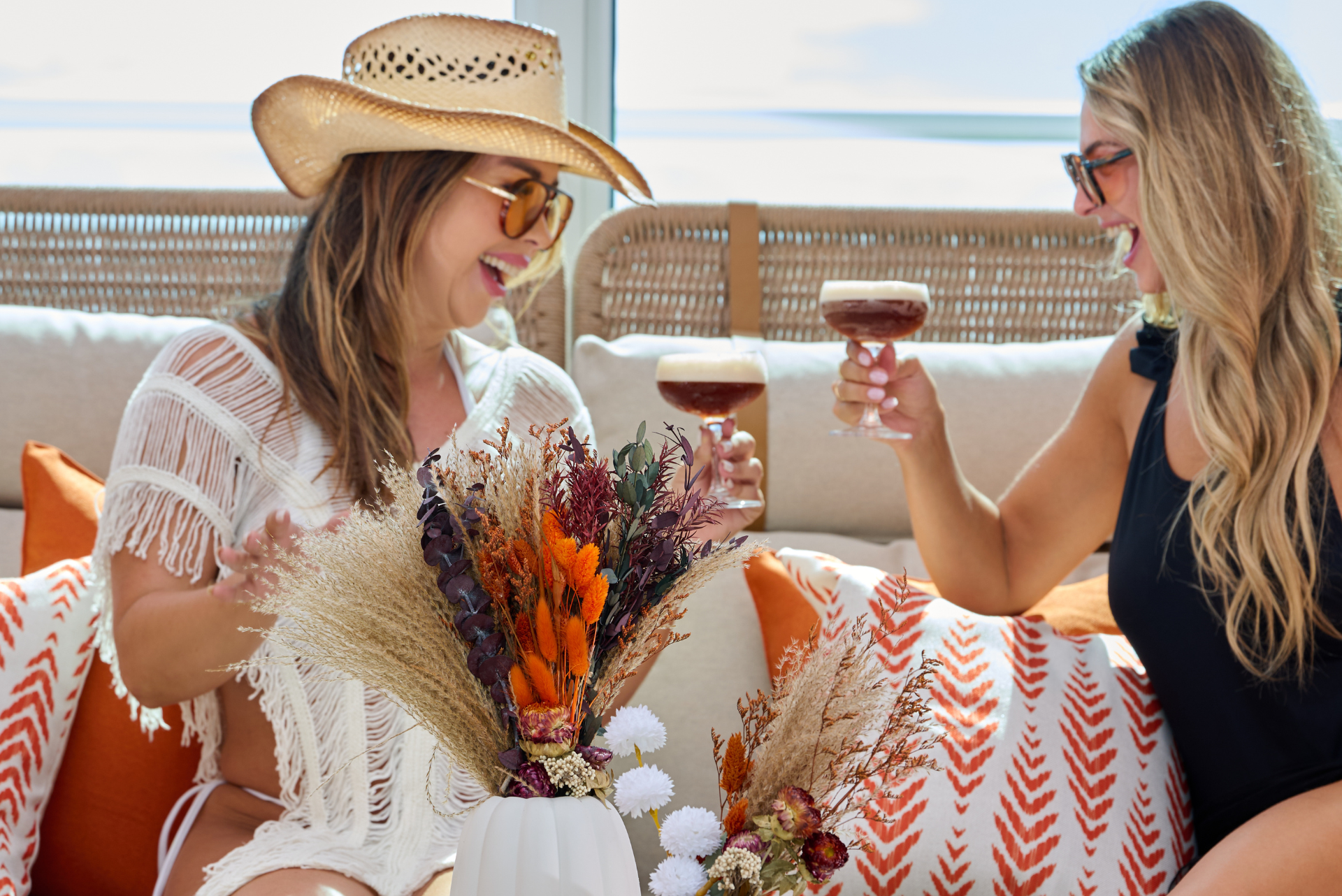 two women sitting on a couch with drinks