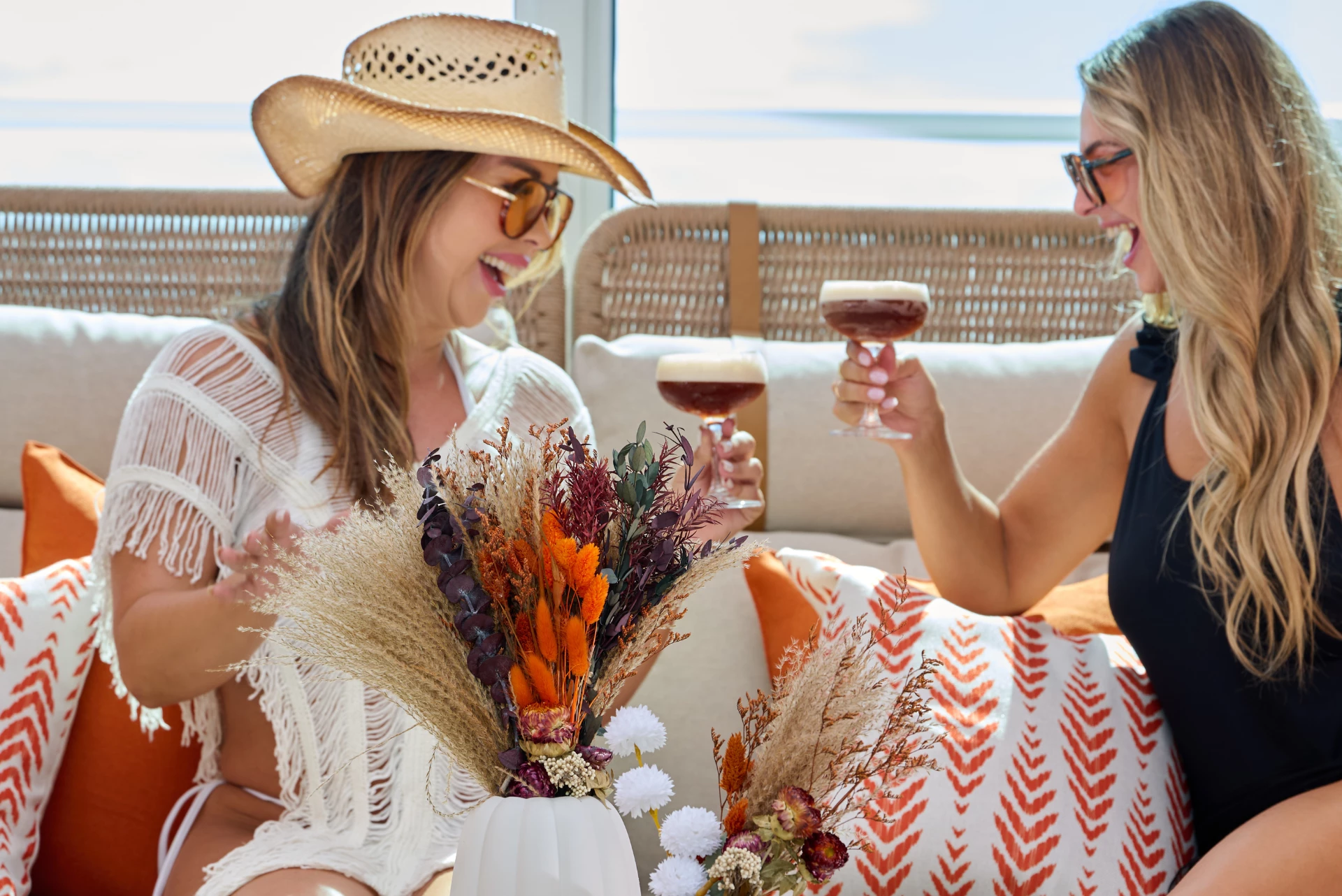 two women sitting on a couch with drinks