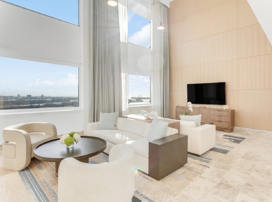 a living room with a large window, a tv and upholstered furniture