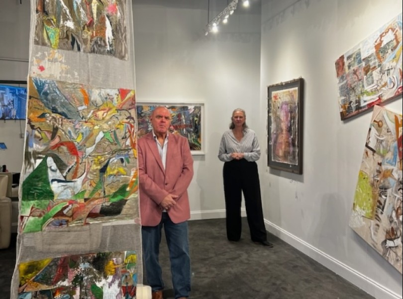 a man and woman standing in a room with art