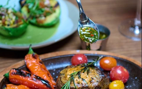a person pouring sauce on a plate of food