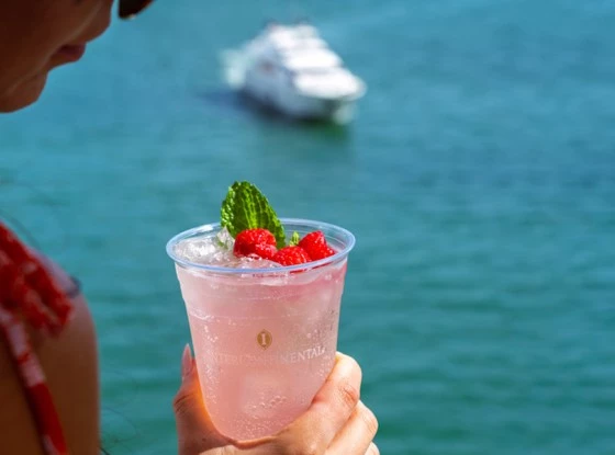 a boat in the background while a lady is holding a drink