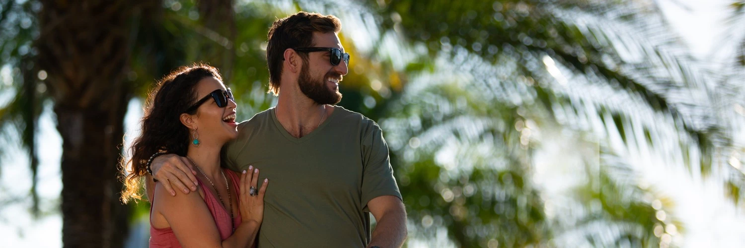 a couple walking through miami together smiling with palm trees all around them