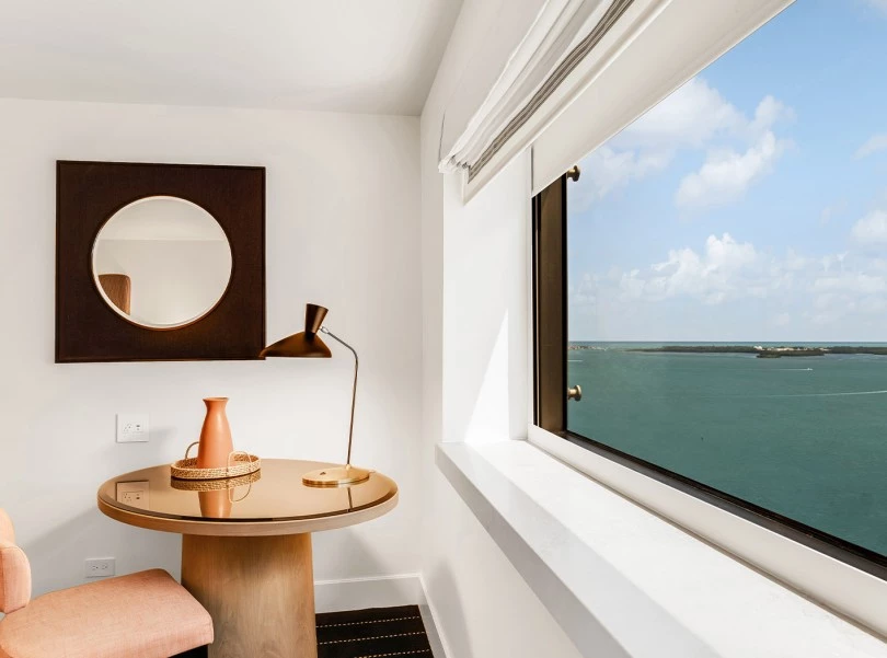 a room with a table and a window with a view of the ocean