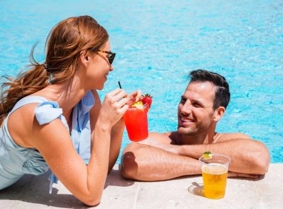 a couple sipping drinks together by the pool