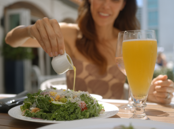 a woman pouring a sauce on a plate of salad