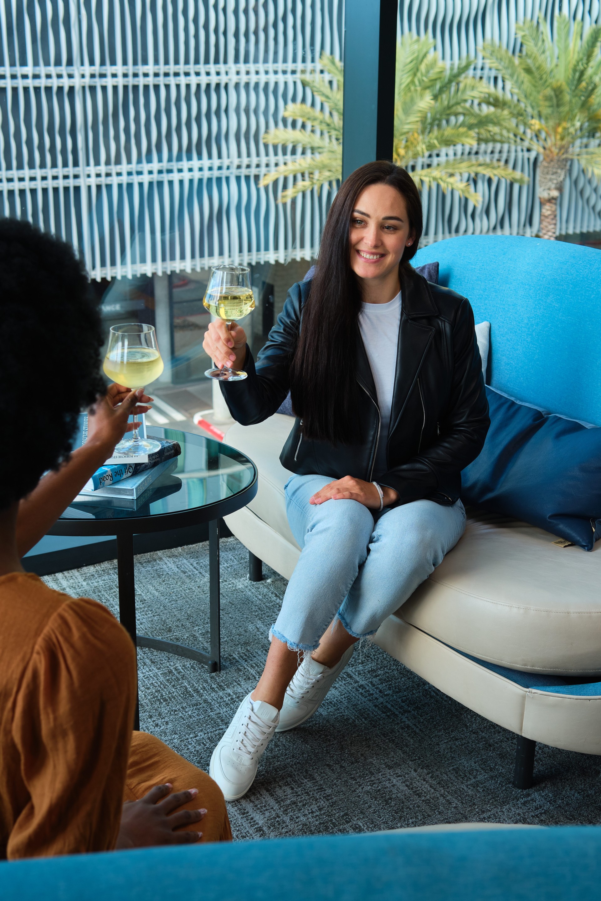 a woman sitting on a couch holding wine glasses