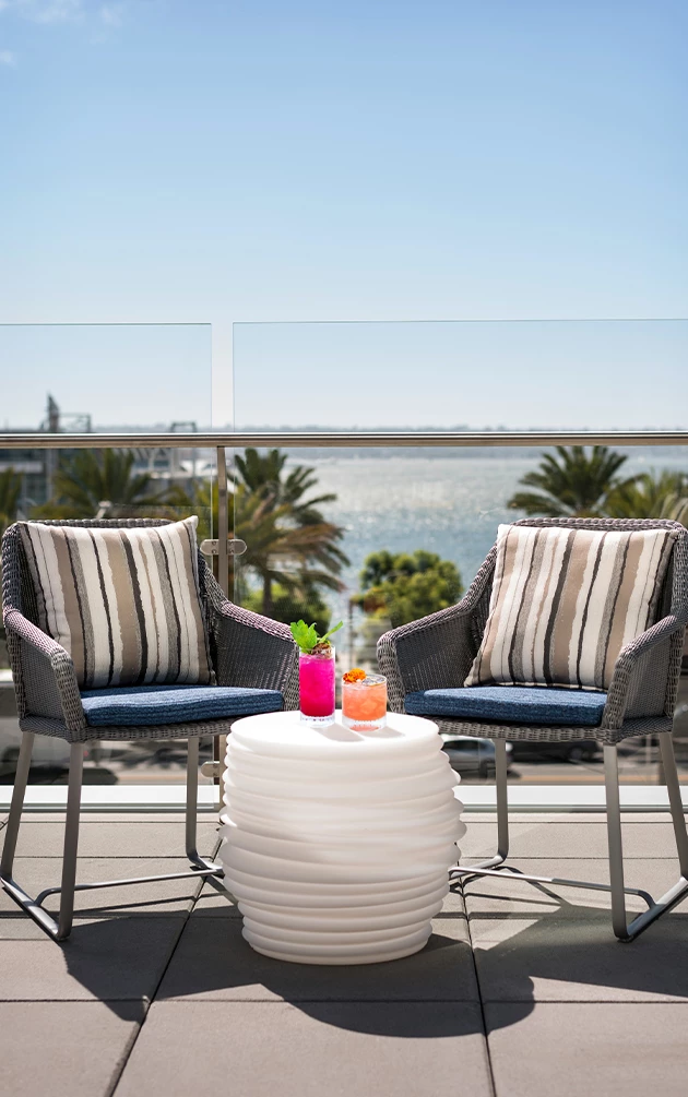 two chairs on a patio with a table with drinks on it