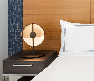 a lamp on a nightstand next to a bed